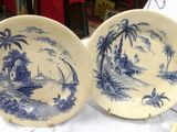 pair of blue and white plates with palm trees on them on a table