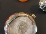 three silver vases on a table with oranges in the background