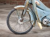 a old blue motorcycle parked in front of a brick wall