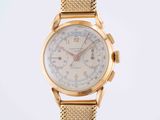a close up of a gold watch with a mesh band