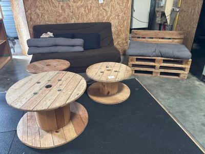 trois bobines en bois posées par terre dans une pièce