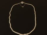 un collier de perles blanches avec un fermoir en diamant