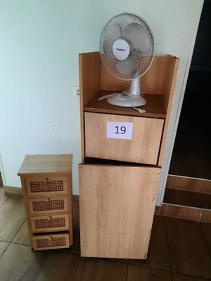 a fan that is sitting on top of a wooden cabinet