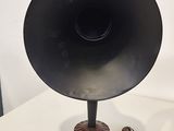 a black speaker sitting on top of a table next to a pair of shoes