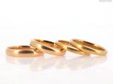 three gold wedding rings sitting on top of a white surface