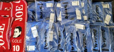 many bags of blue shirts and a red scarf on display