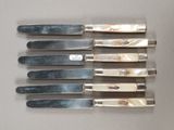 six knives are lined up on a table with a white background