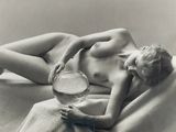 a nude woman laying on a bed with a bowl of water
