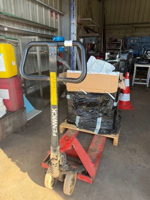 un chariot à roulettes sur lequel est posée une caisse, dans un entrepôt