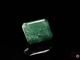 an emerald stone sitting on top of a black surface