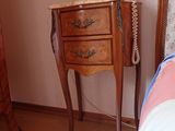 a small table with a telephone on it next to a bed