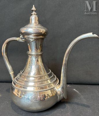 cafetière plaquée argent avec une anse incurvée sur fond noir