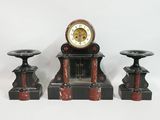une horloge posée sur une table, à côté de deux bougies