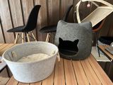 a black cat sitting in a cat bed on a table