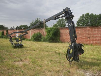 a crane that is sitting in the grass near a brick wall
