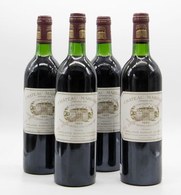 quatre bouteilles de vin sont alignées sur une surface blanche