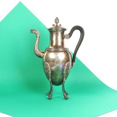 une théière en argent posée sur une surface verte