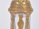 a small glass jar with a gold decoration on top of it