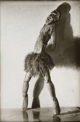 black and white photograph of a woman in a feathered dress holding a cell phone to her ear