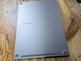 the back of a silver laptop sitting on top of a wooden table