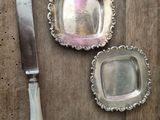 three silver dishes and a knife on a wooden table