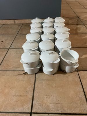 beaucoup de casseroles et poêles blanches posées par terre