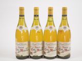 quatre bouteilles de vin sont alignées sur une surface blanche