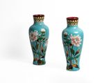 une paire de vases bleus ornés de fleurs roses sur fond blanc