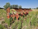 une rangée de vieux outils agricoles dans un champ d'herbes hautes