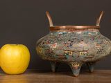 a yellow apple next to a decorative pot on a table