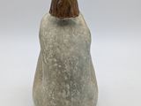 figurine of a woman sitting on a rock with her back to the camera