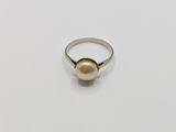 a pearl ring on a white surface