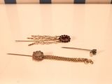 deux paires de boucles d'oreilles avec des chaînes et des perles posées sur une table blanche