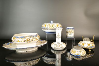 a black table with a white and gold plate and cups and saucers on it