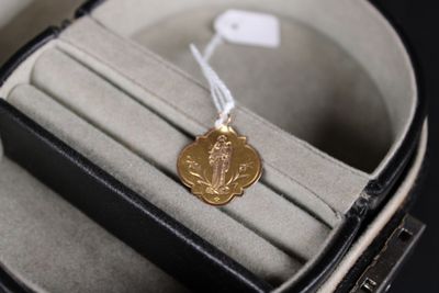 une médaille d'or dans un écrin noir posé sur une table noire