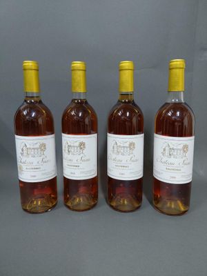 quatre bouteilles de vin sont alignées sur une surface grise