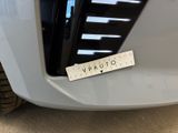 a close up of the front bumper of a white car with a sticker on it