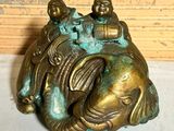 a bronze statue of a fish and two people sitting on top of it