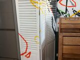 un graffiti sur le mur d'une salle de bains équipée d'un meuble blanc et d'une chaise en bois