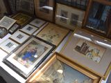 many framed pictures on a table with a white table cloth