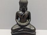 statue of a person sitting in a meditation position on a white surface