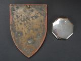 a metal shield and a mirror on a black surface