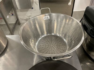 a large metal colander sitting on top of a kitchen counter
