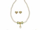 un ensemble composé d'un collier et d'un bracelet en perles blanches, rehaussés de touches de vert et d'or