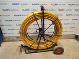a yellow hose sitting on a cart in front of a wall