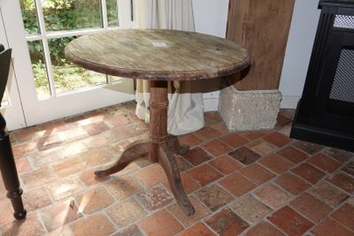 une petite table avec un plateau en bois posée sur un sol en briques