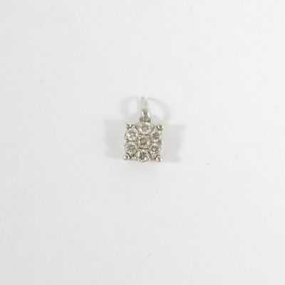 un gros plan d'un petit pendentif en diamant posé sur une surface blanche
