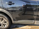 the reflection of a man in a black jacket is on the side of a car