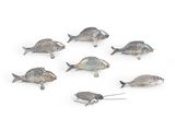 Des figurines de poissons argentés sont disposées en cercle sur une surface blanche