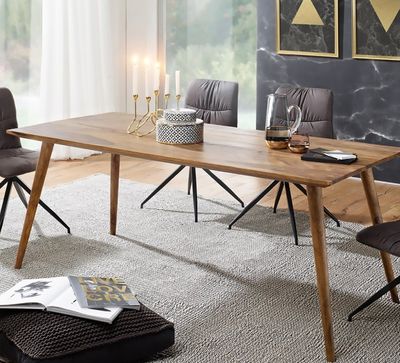 a dining room table with chairs and a rug on the floor